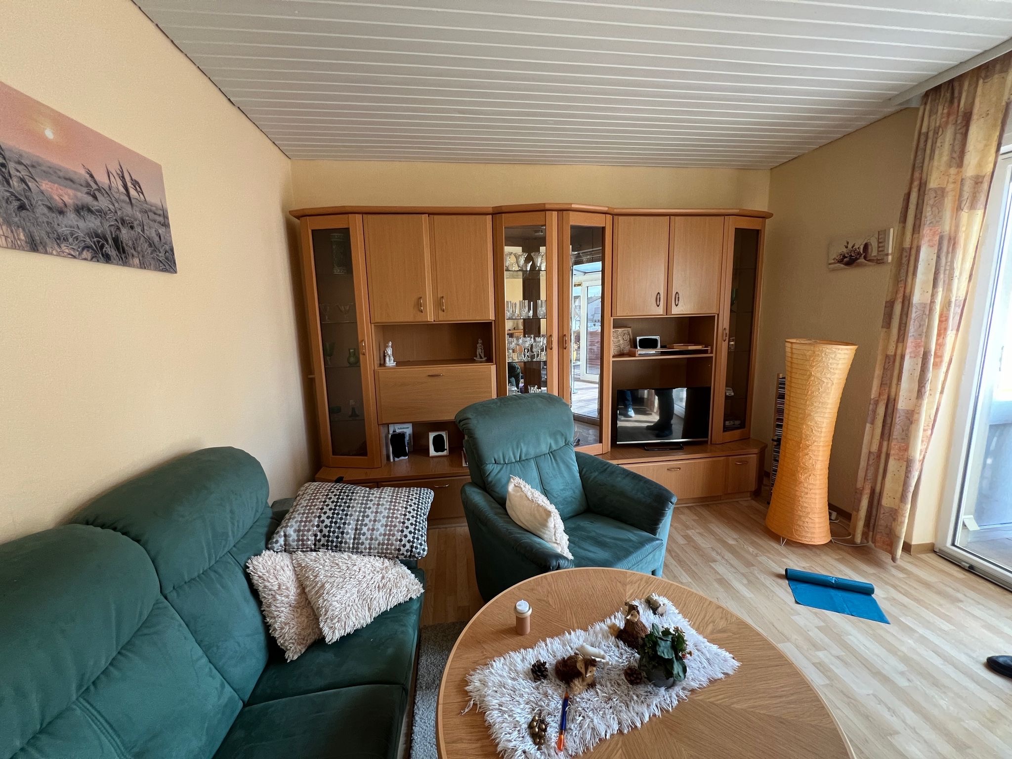 Ein gemütliches Wohnzimmer mit grünen Sesseln, Holzmöbeln und Dekoration.