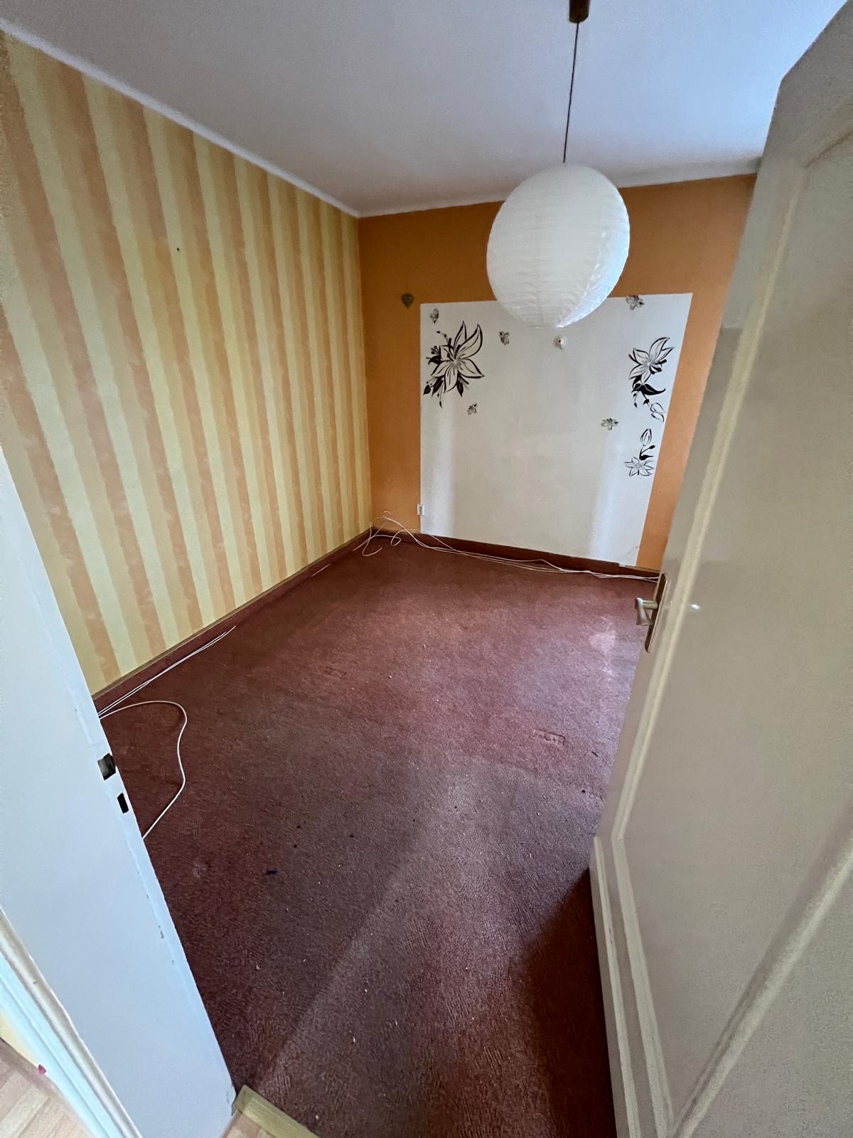 Ein leeres Zimmer mit gelb gestreiften Wänden und einem großen runden Lampenschirm.